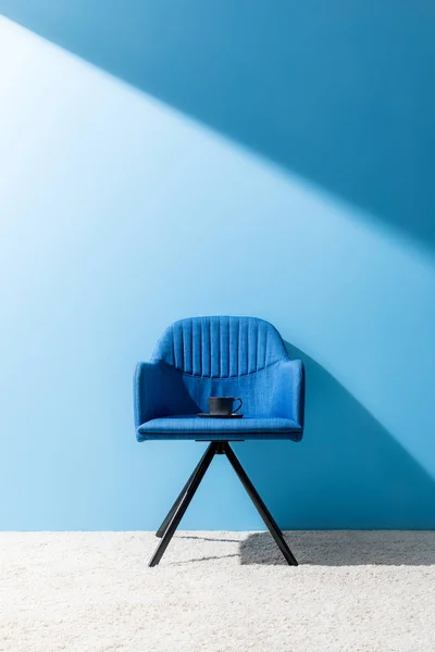 Taza de delicioso café en la silla delante de la pared azul - foto de stock