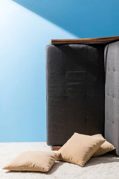 Диван с перевернутыми на бок подушками перед синей стеной — стоковое фото
