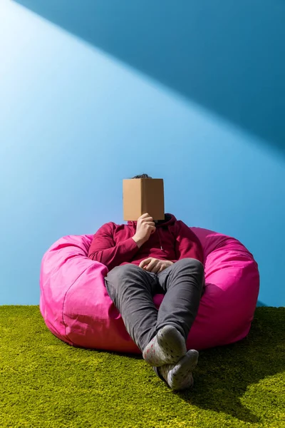 Man reading book in bean bag in front of blue wall — Stock Photo