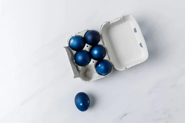 Vista dall'alto di uova di Pasqua dipinte di blu in vassoio di uovo su bianco — Foto stock