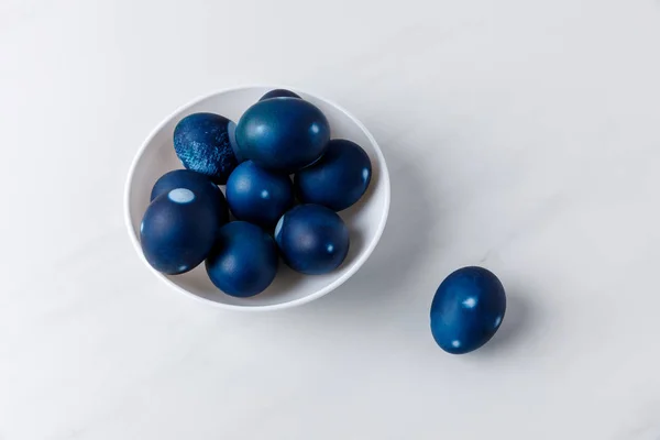 Huevos de Pascua pintados de azul en un tazón sobre una superficie blanca - foto de stock