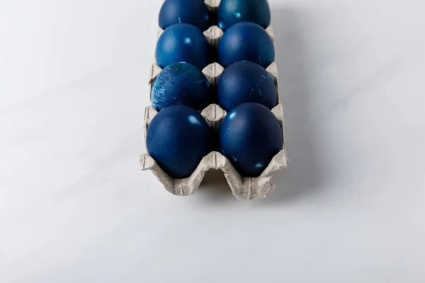 Huevos de Pascua pintados de azul en bandeja de huevo sobre mesa blanca - foto de stock