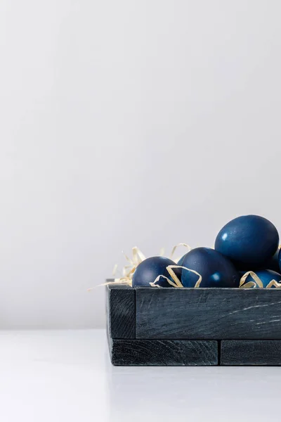 Голубые окрашенные пасхальные яйца в коробке с декоративным сеном — стоковое фото