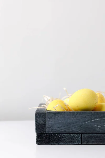 Yellow painted easter eggs in wooden box on white table — Stock Photo