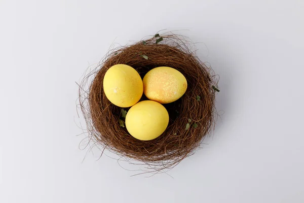 Vue de dessus des œufs de Pâques peints en jaune dans le nid décoratif sur blanc — Photo de stock