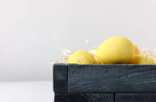 Oeufs de Pâques peints en jaune dans une boîte en bois sur blanc — Photo de stock