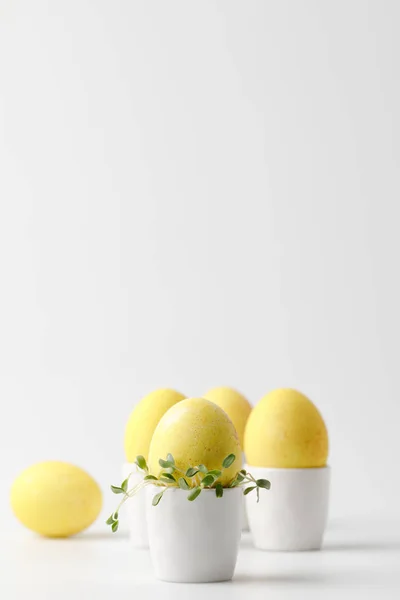 Huevos de Pascua pintados de amarillo en puestos de huevo sobre blanco - foto de stock