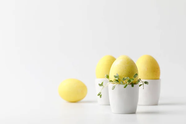 Huevos de Pascua pintados de amarillo en puestos de huevo sobre blanco - foto de stock