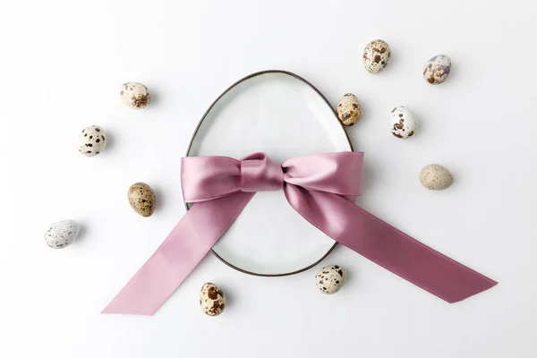 Vue de dessus de la plaque en forme d'oeuf avec des oeufs de caille sur blanc, concept de Pâques — Photo de stock