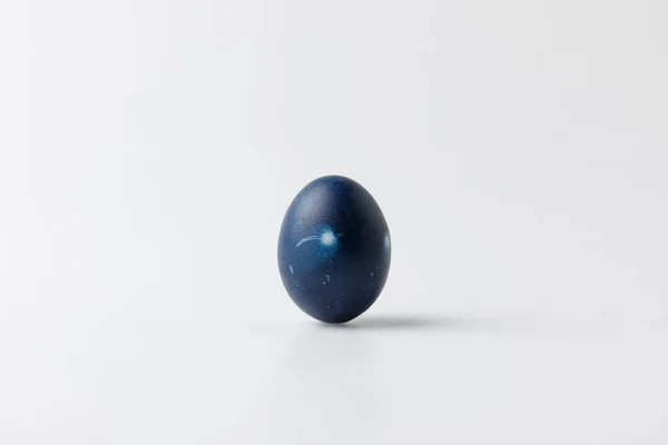 Un huevo de Pascua pintado de azul sobre blanco - foto de stock