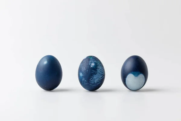 Три сині розфарбовані великодні яйця на білій поверхні — стокове фото