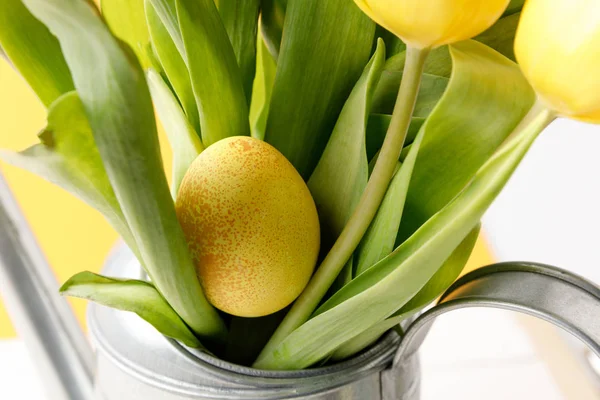 Huevo de Pascua pintado amarillo en ramo de tulipanes - foto de stock