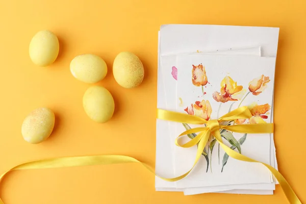 Vue du dessus des œufs de Pâques peints en jaune avec cartes postales sur jaune — Photo de stock
