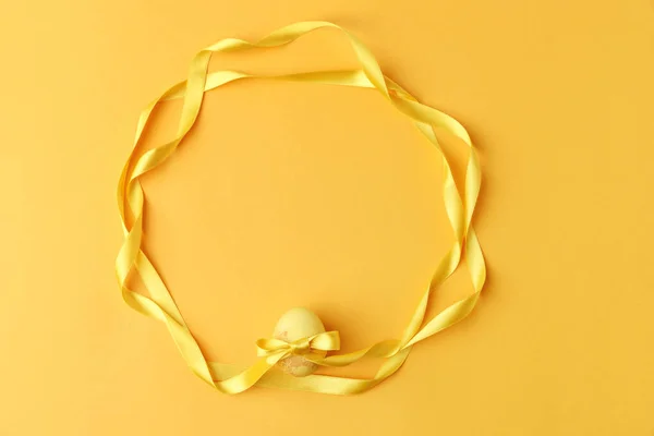 Top view of yellow painted easter egg with ribbons on yellow — Stock Photo