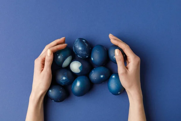 Imagen recortada de la mujer tocando huevos de Pascua pintados de azul - foto de stock
