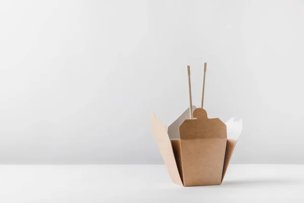 Caixa de macarrão com pauzinhos em mesa branca — Fotografia de Stock