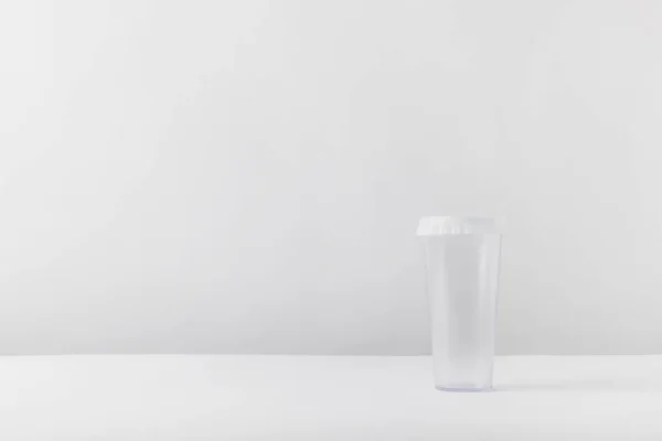 Un vaso de plástico sobre una mesa blanca - foto de stock