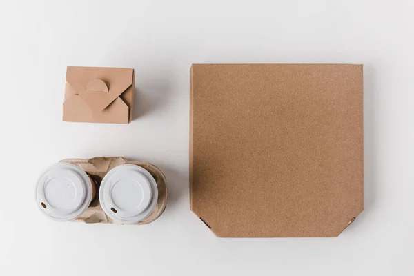 Top view of pizza box and disposable coffee cups with noodles box on white — Stock Photo