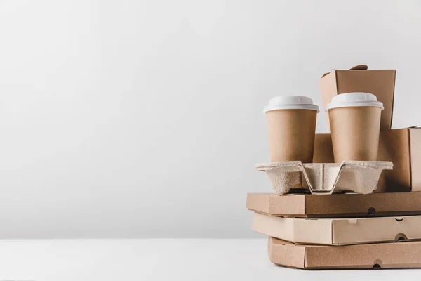 Scatole di pizza e tazze di caffè usa e getta con scatole di tagliatelle su tavolo — Foto stock