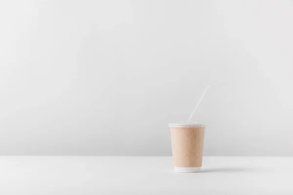 Uma xícara de café descartável na mesa branca — Fotografia de Stock