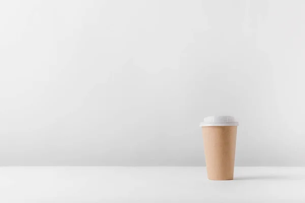 Taza de café desechable en la superficie blanca - foto de stock