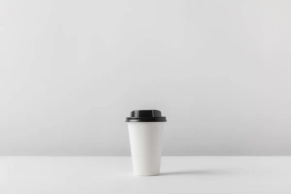 Taza de café desechable en la mesa blanca - foto de stock