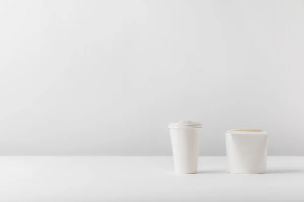 Disposable coffee cup and noodles box on white surface — Stock Photo