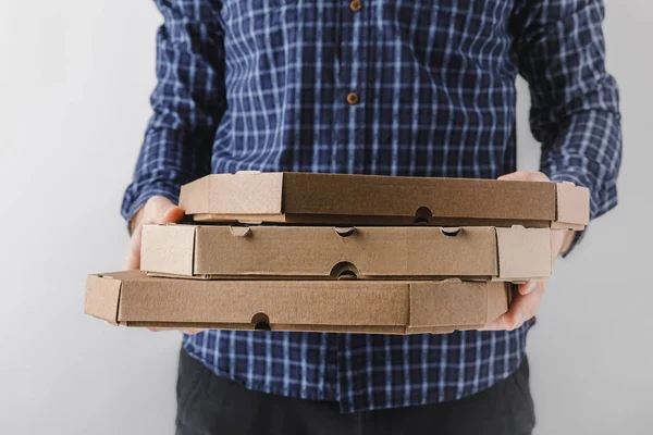 Abgeschnittenes Bild eines Kuriers, der drei Pizzakartons isoliert auf grau hält — Stockfoto