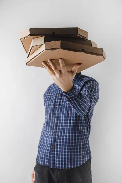 Mensajero sosteniendo cajas de pizza por un lado aislado en blanco - foto de stock