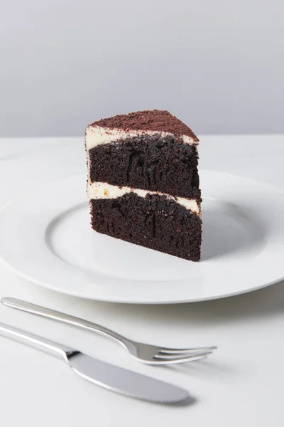 Vista de perto do bolo de chocolate na placa branca colocada na superfície branca — Fotografia de Stock