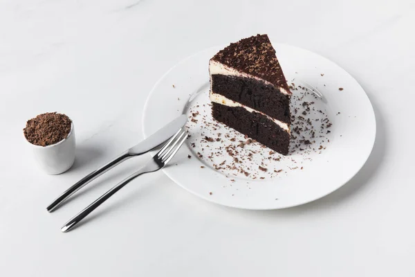 Geriebene Schokolade in Schüssel, Besteck und Kuchen auf Teller — Stockfoto