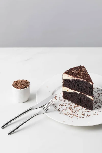 Geriebene Schokolade in Schüssel mit Kuchen auf Teller auf weißer Oberfläche — Stockfoto