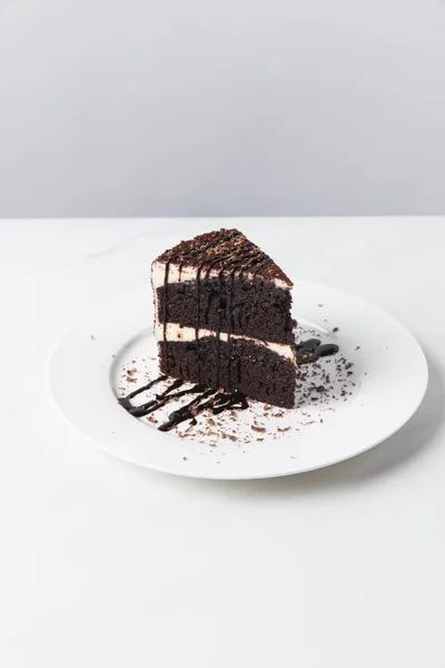 Vorderseite des Schokoladenkuchens mit Glasur auf Teller auf weißer Oberfläche — Stockfoto