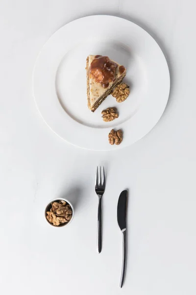 Cake with bowl of walnuts placed on white surface — Stock Photo