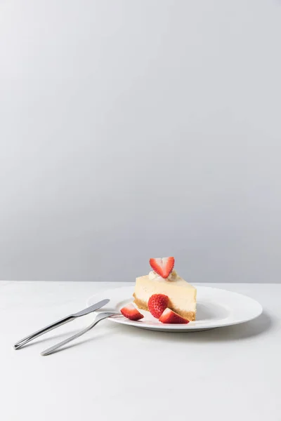 Trozos de fresas frescas en el plato con tarta de queso - foto de stock