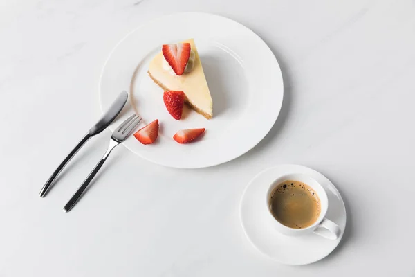 Coffee cup with strawberry cheesecake on plate and cutlery — Stock Photo