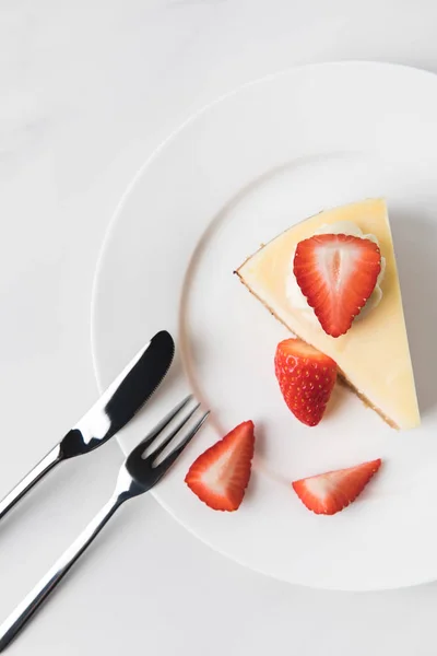 Vista superior de cheesecake com morangos e talheres em branco — Fotografia de Stock