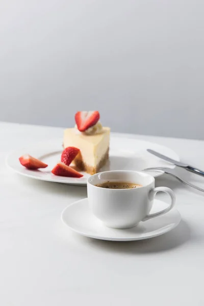 Bolo de queijo com morangos no prato e xícara de café em primeiro plano — Fotografia de Stock