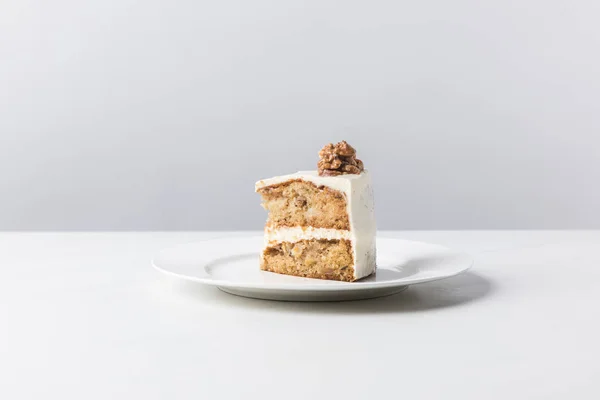 Plate with cake and walnut on top on white surface — Stock Photo