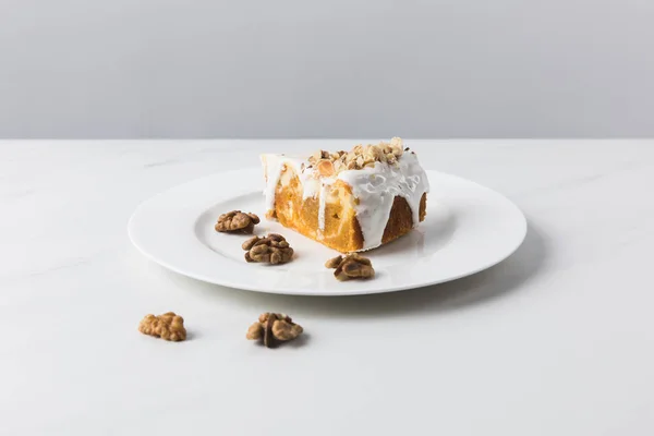 Closeup view of plate with cake surrounding by walnuts placed on white surface — Stock Photo