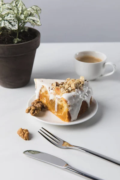Kaffeetasse, Kuchen und Besteck mit Topfpflanze auf dem Tisch — Stockfoto