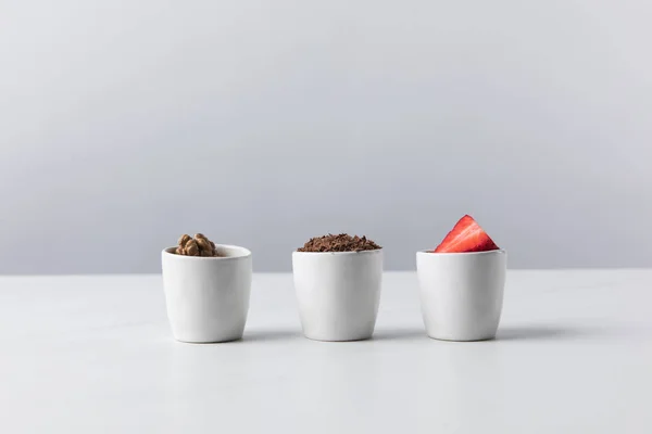 Vorderseite von drei Schalen mit Walnüssen, geriebener Schokolade und Erdbeeren — Stockfoto