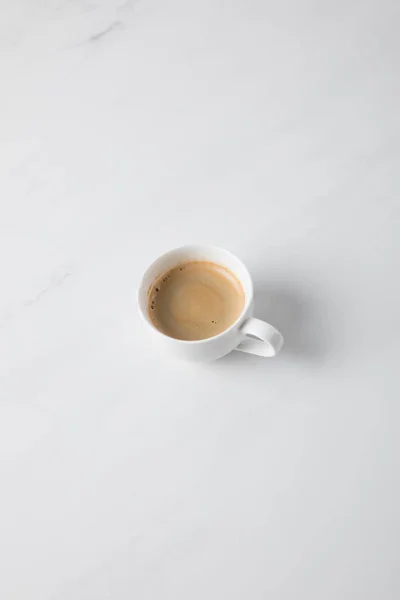 Vista superior de la taza de café colocada en la superficie blanca - foto de stock