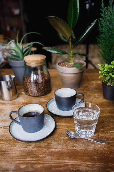 Tazze di caffè e bicchiere d'acqua sul tavolo del caffè — Foto stock