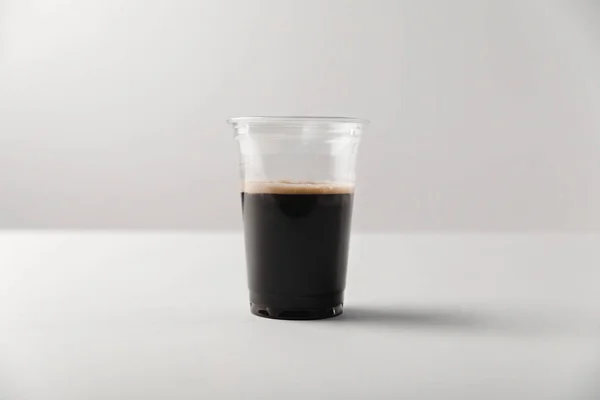 Tazza usa e getta con caffè nero su sfondo bianco — Foto stock