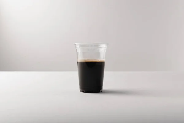 Taza de plástico con café negro sobre fondo blanco - foto de stock