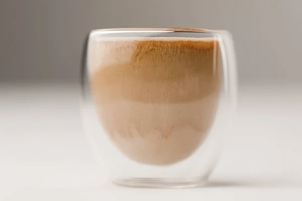 Copa de vidrio llena de café con leche sobre fondo blanco - foto de stock