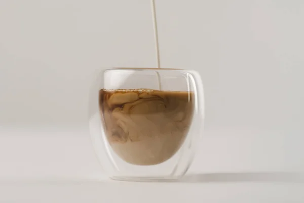 Verser le lait dans une tasse avec du café isolé sur fond blanc — Photo de stock