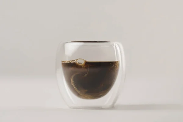 Remolinos de leche en vaso de doble pared con café sobre fondo blanco - foto de stock