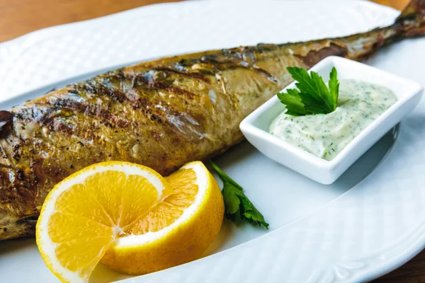 Close-up view of delicious grilled mackerel with sauce and lemon slices — Stock Photo